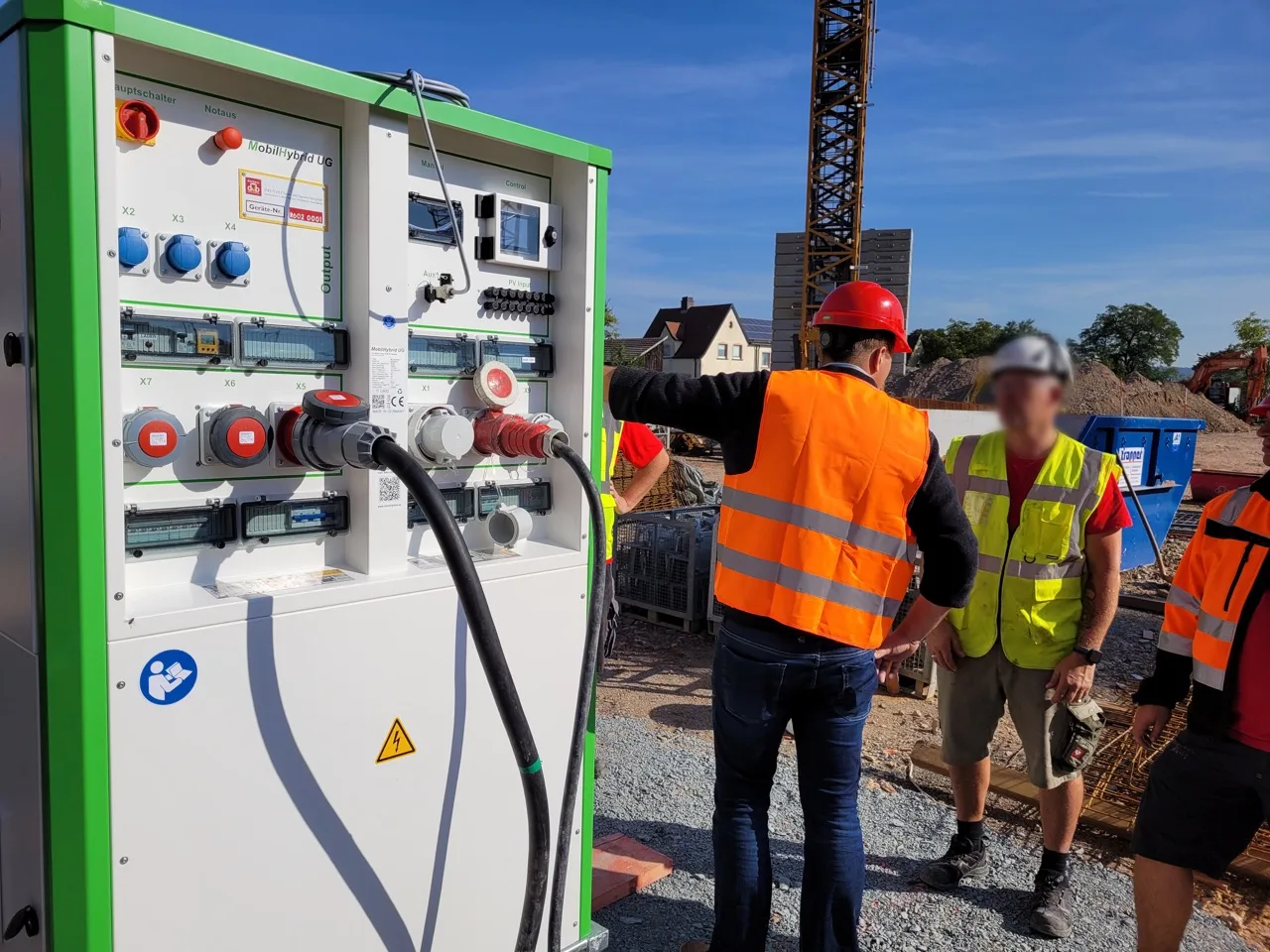 Geöffneter MobilHybrid auf einer Baustelle mit Baukran und Baupersonal